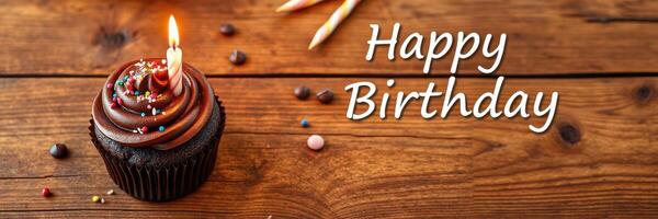 Chocolate cupcake decorated with sprinkles and a candle celebrates a birthday on a wooden table photo