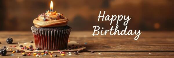 Birthday cupcake with chocolate frosting and candle on wooden table with festive decorations photo