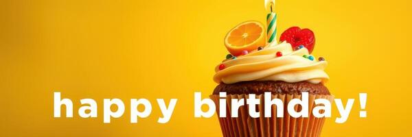 Colorful birthday cupcake decorated with frosting and fruit sitting against a bright yellow background photo