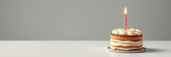 Delicious layered cake with a single candle placed on a white table against a plain backdrop photo