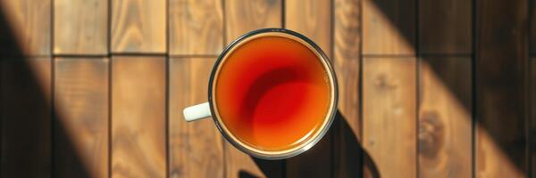 Warm cup of tea resting on wooden table in afternoon light showcasing rich color and tranquil atmosphere photo