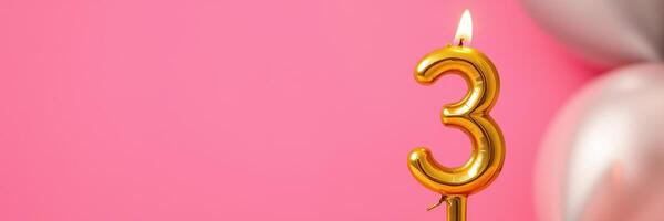 Celebratory gold number three candle shining brightly against a pink backdrop with balloons for a joyful birthday party photo