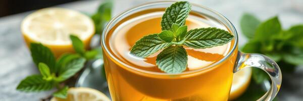 Refreshing herbal tea served in a glass cup with mint leaves and lemon slices on a marble table photo