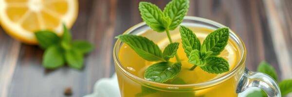 Refreshing herbal drink with mint leaves and lemon slice served in a glass on wooden table photo