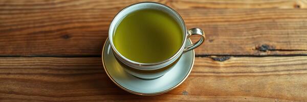 Green tea served in a delicate cup on a rustic wooden table in a cozy cafe setting during the afternoon photo