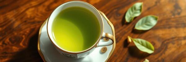 Freshly brewed green tea in an elegant cup with leaves on a wooden table photo