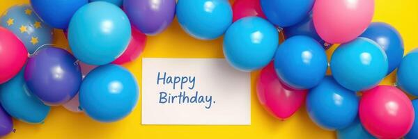 Decorated birthday setting with colorful balloons and a greeting card on a bright yellow background photo