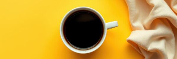 Black coffee in a white cup on a vibrant yellow background with soft fabric photo