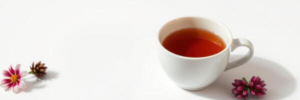 Warm cup of tea beside blooming flowers on a white surface during a bright afternoon photo