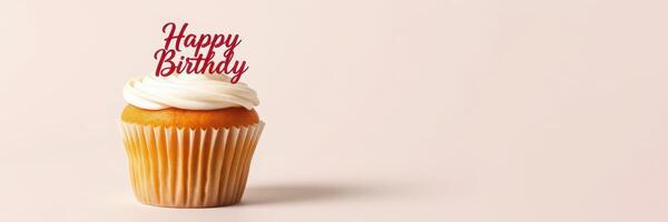 Celebratory birthday cupcake with cream frosting and festive topper on a plain background photo