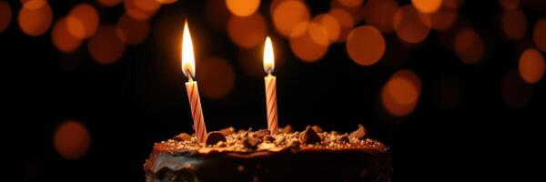 Celebratory birthday cake with two candles glowing against a festive backdrop of warm lights photo