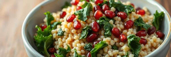 Colorful and nutritious salad with pearl couscous, pomegranate seeds, and fresh greens in a bowl on wooden table photo