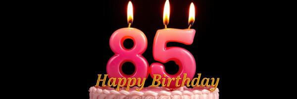 Celebration of an 85th birthday with a cake featuring pink candles and joyful wishes photo