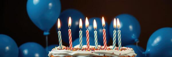Celebration with birthday cake featuring lit candles and blue balloons in the background photo