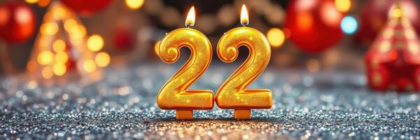 Festive golden number candles representing 22 on a sparkling surface with holiday decorations in the background photo
