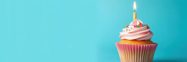 Colorful cupcake with a pink swirl frosting and a single candle celebrating a birthday photo