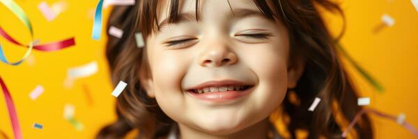 Joyful child celebrating with confetti against a bright yellow background during a festive occasion photo