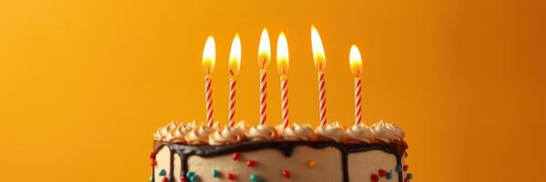 Special birthday cake with lit candles against a vibrant orange background photo