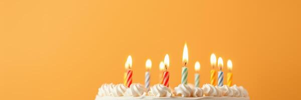 Celebrate a joyful birthday with a decorated cake featuring glowing candles against a vibrant orange background photo