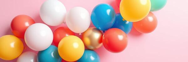 Colorful balloons of various shapes arranged on a pastel pink surface for a festive celebration photo