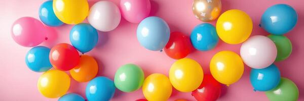 Colorful balloons scattered on a pink background create a festive atmosphere for celebrations and parties photo