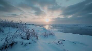 A snowy beach with a sun setting in the background photo