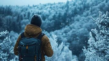 A man wearing a brown jacket and a blue backpack is standing in the snow photo