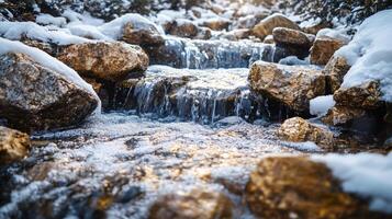 A stream of water flows through a rocky area covered in snow photo