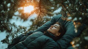 A woman is sleeping in a forest with a blanket and a jacket photo