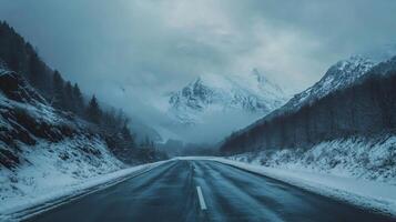 A snowy mountain range is in the background of a road photo