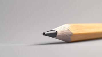 A pencil with a black tip is on a grey surface photo