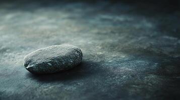 A large rock sits on a grey surface photo