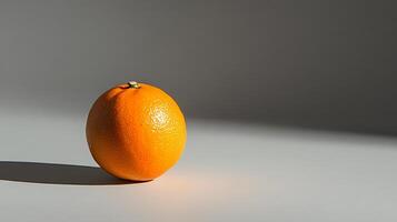A single orange sits on a table in front of a window photo