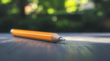 A pencil is laying on a table with a green background photo