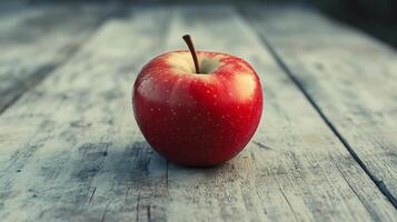 A red apple sits on a wooden table photo