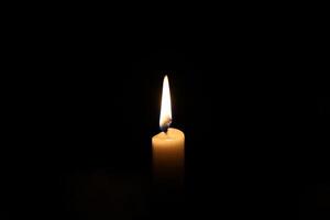 Paraffin candle in complete darkness, light in the darkness photo