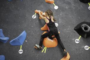 Courageous girl climbing artificial rock wall at bouldering gym photo