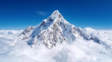 Stunning snowy mountain peak surrounded by clouds and blue sky photo