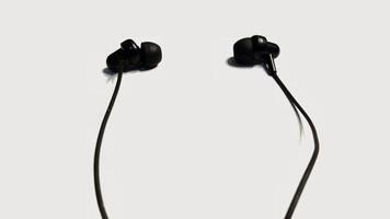 Pair of black wired earphones isolated on white background. Technology, music, audio, listening concept. photo