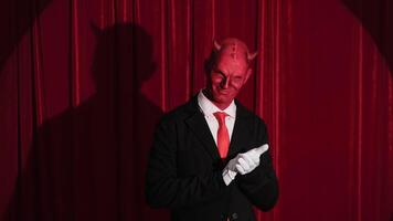 Devilish businessman pointing with white gloves on red stage video