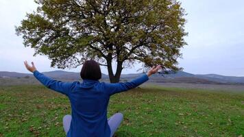 Back view of unrecognizable slender young woman in lotus position video