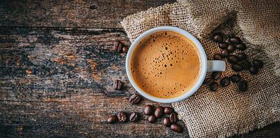 Coffee cup with steam and coffee beans on a wooden background. A cup of hot espresso or black latte, with a burlap sack on an old, rustic table photo