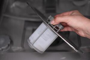 woman's hand checking the filter in the dishwasher photo