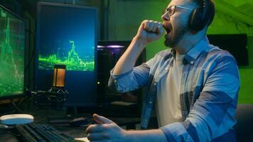 Exhausted Caucasian guy crypto trader broker man working overtime late night tiredness. Male worker yawn trading stock deadline at home neon freelancer typing computer software overwork programming photo