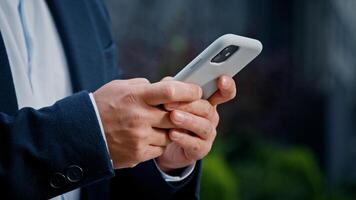 Close up male hands typing texting browsing mobile phone. Unrecognizable unknown man businessman in formal suit working with smartphone in city outdoors manager managing project remote with telephone photo