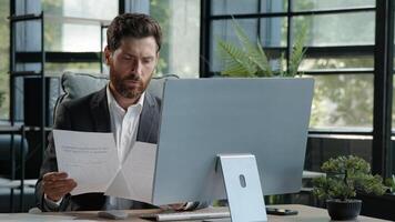 Busy Caucasian pensive man boss manager adult 40s businessman sitting in office work with paperwork and computer check data in papers search information look at screen corporate company app project photo
