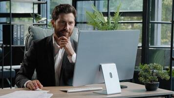 Busy adult 40s bearded pensive thoughtful businessman working at computer in office online job. Professional employee worker typing thinking over internet project has problem with mistake in website photo