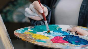 Closeup woman female hand artist painter paints draws creating new art work on canvas in workshop lesson of painting enjoying process of drawing creating picture using brush applying oil paint palette photo