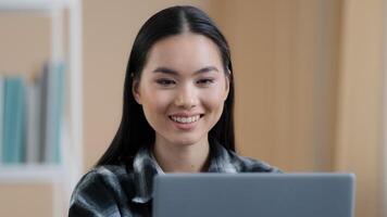 Portrait asian smiling satisfied girl user student freelancer buyer blogger business woman 20s lady looking at laptop screen sincere smile using computer application service website chatting browsing photo