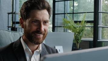 Close-up male worker leader Caucasian businessman bearded mature adult 40s manager looking at window smiling working with computer think about idea chatting online browsing programming job with smile photo